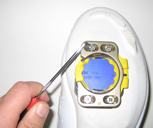 A cycling shoe cleat being cleaned with a screwpick